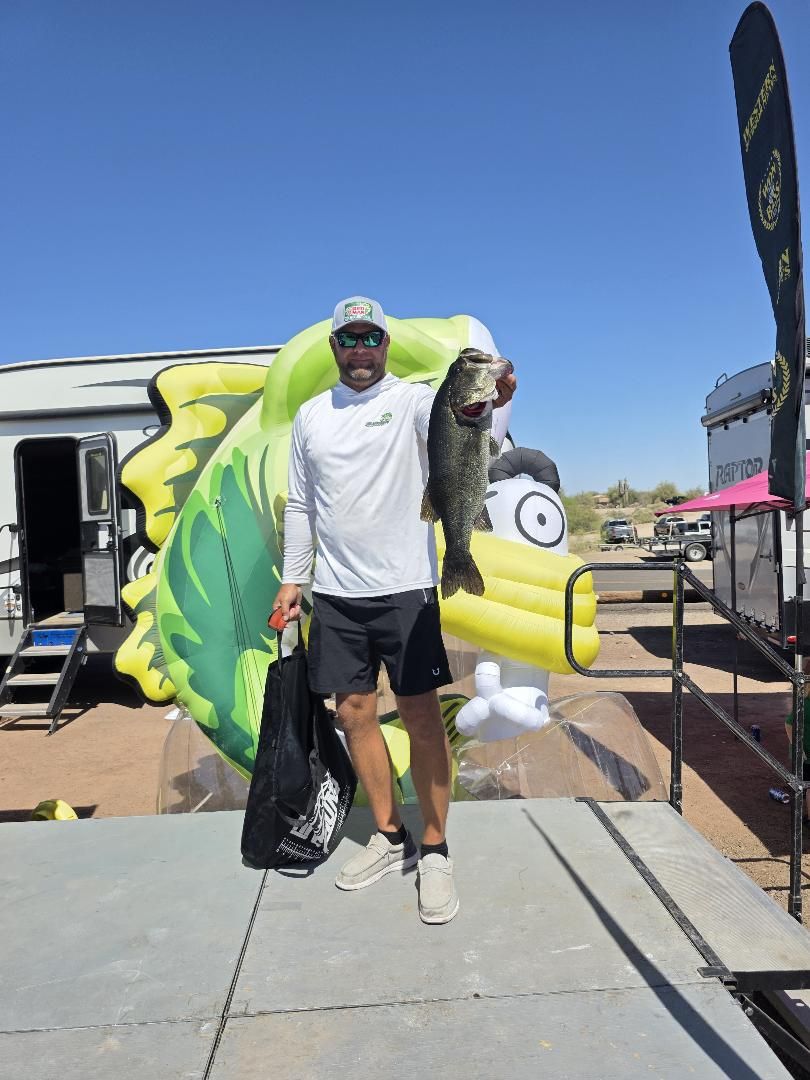 An angler holding a big bass in front of the inflatable Bruce