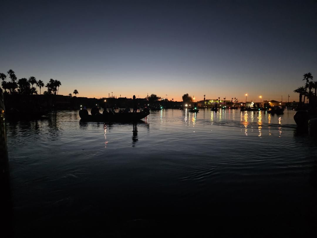 Boats idling on the water under a sunrise sky