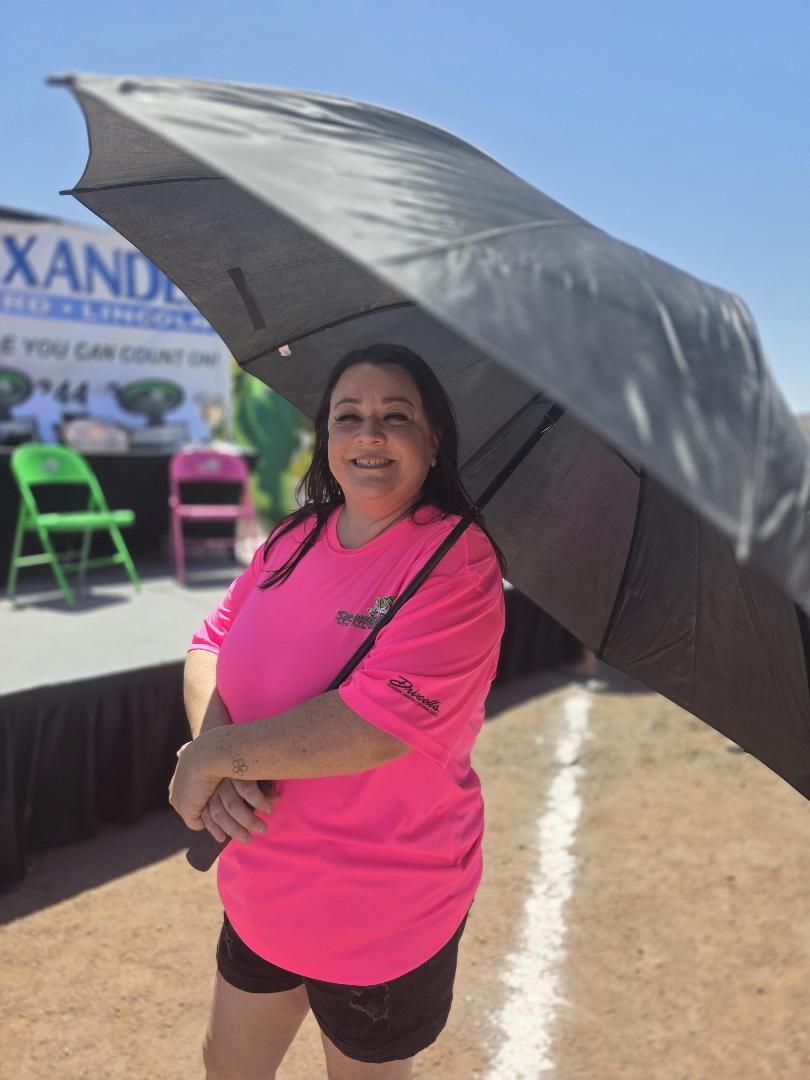 A crew member with an umbrella in front of the stage
