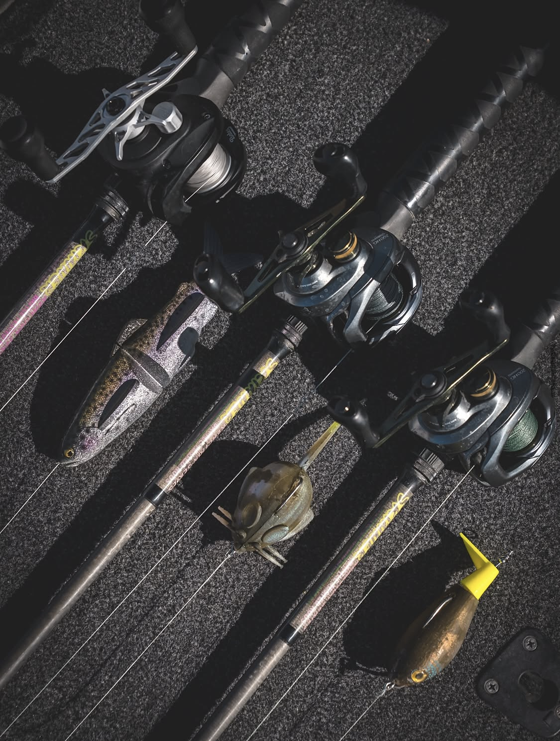 Skinner rods with baitcasting reels laid out on the boat deck beside handmade baits