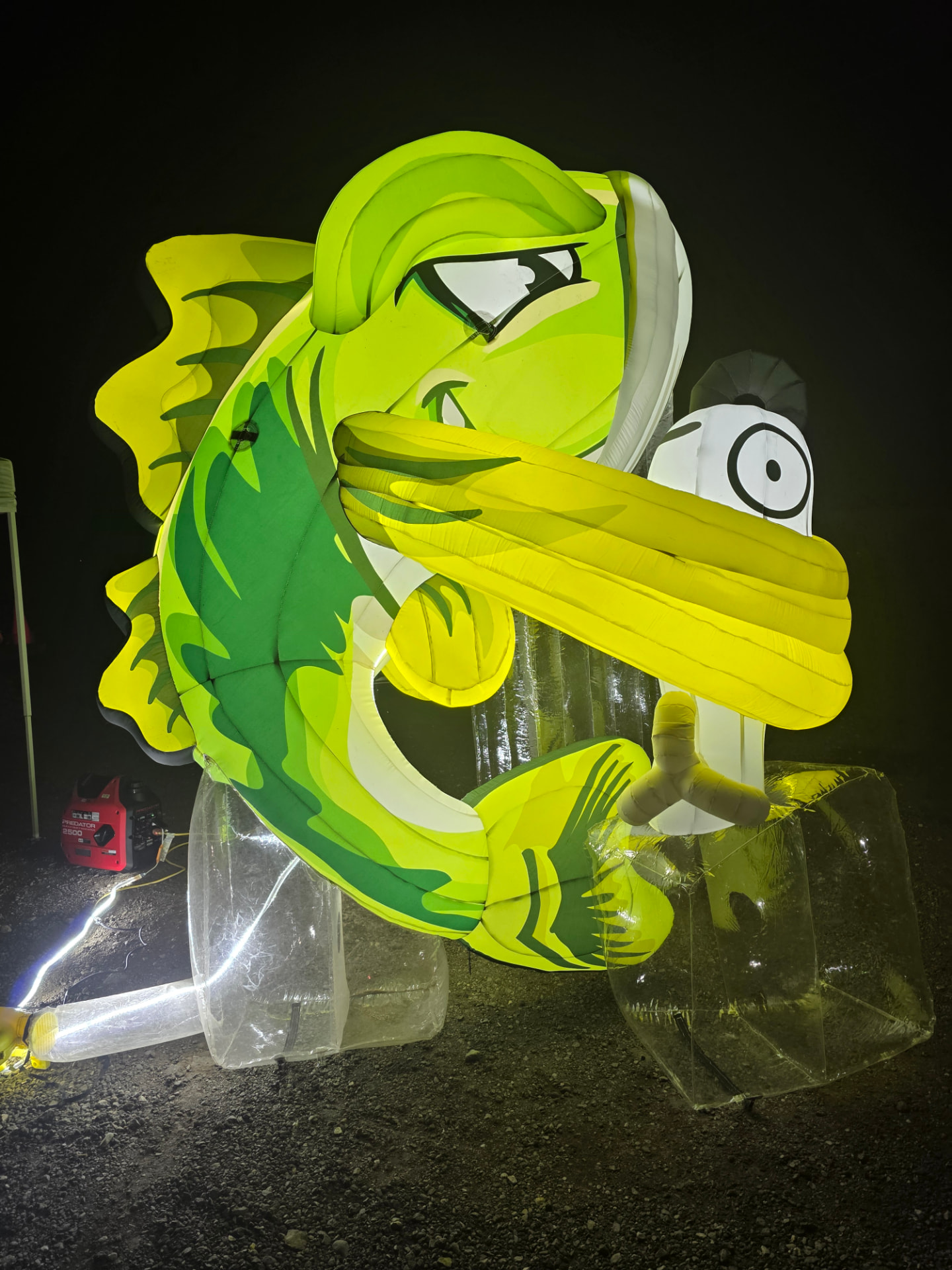 Bruce the Bass, the lit-up green bass mascot of Skinner Baits, curled around a lure at night