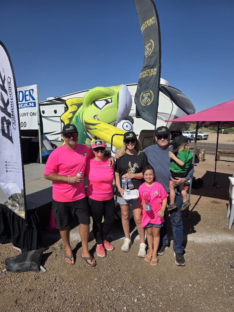 The crew in pink shirts and family posing by the stage